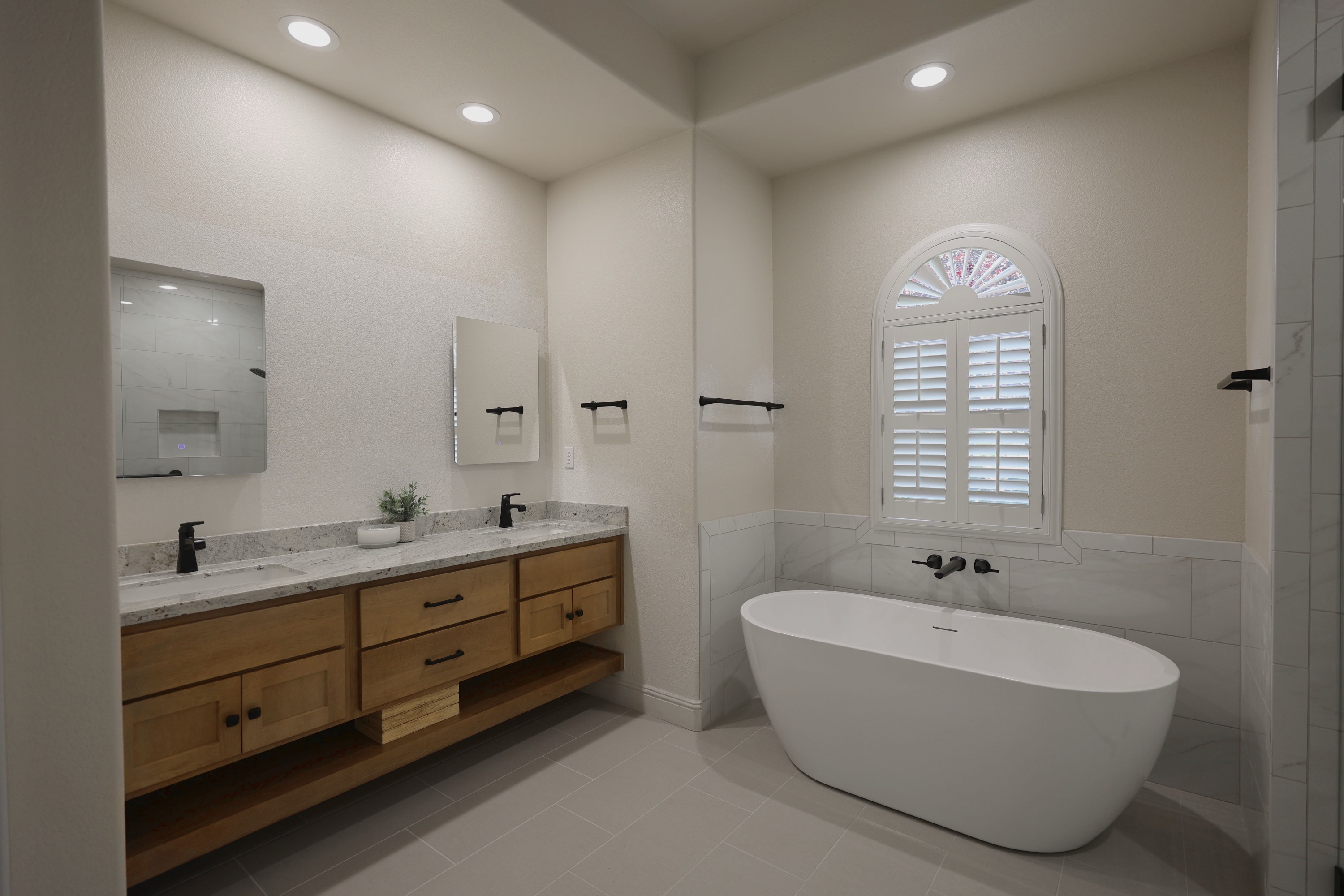 Remodeled master bath with floating wood vanity, granite tops and freestanding soaking tub