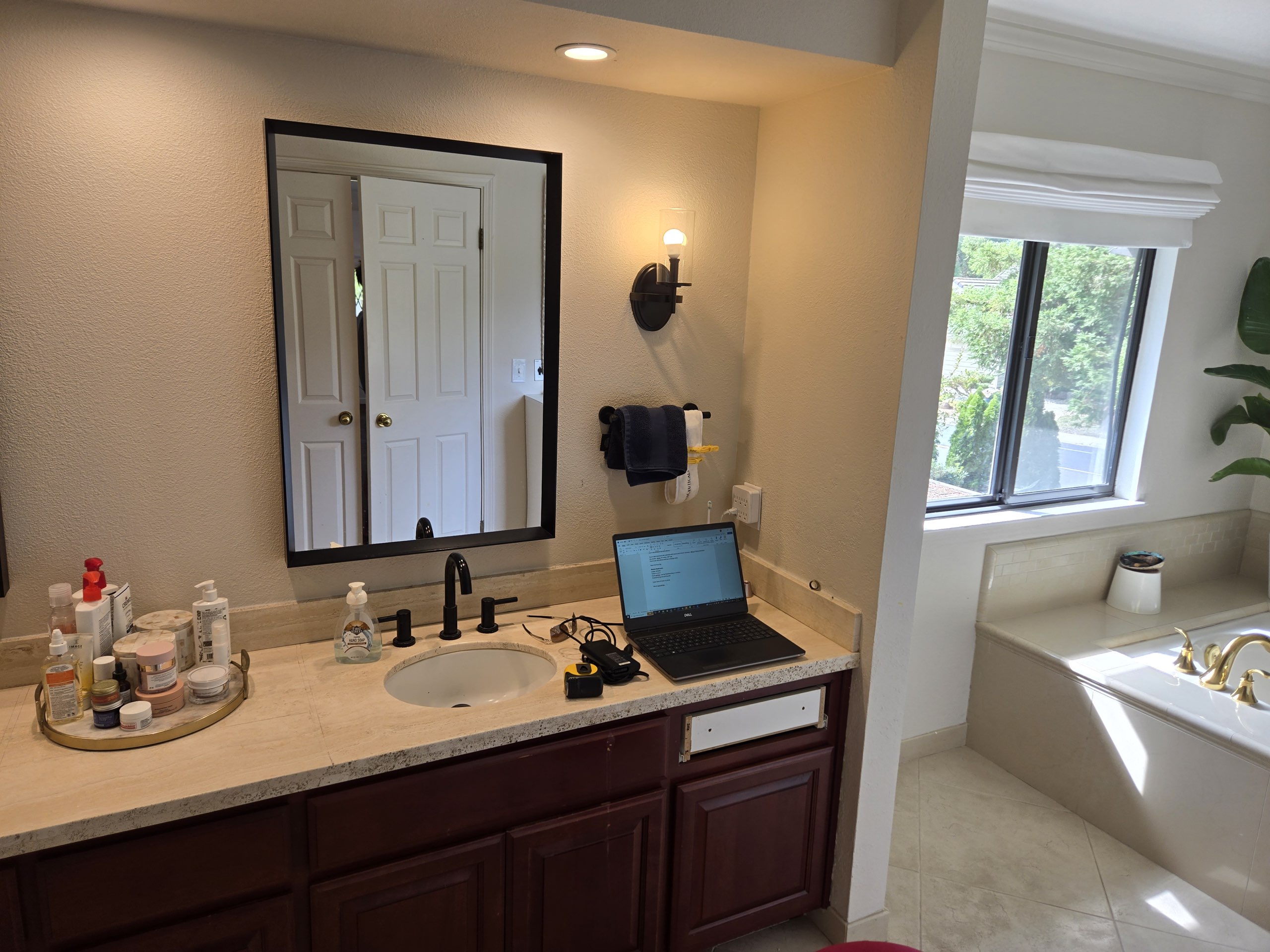 Cluttered bathroom with cherry vanity and dated tile before remodeling