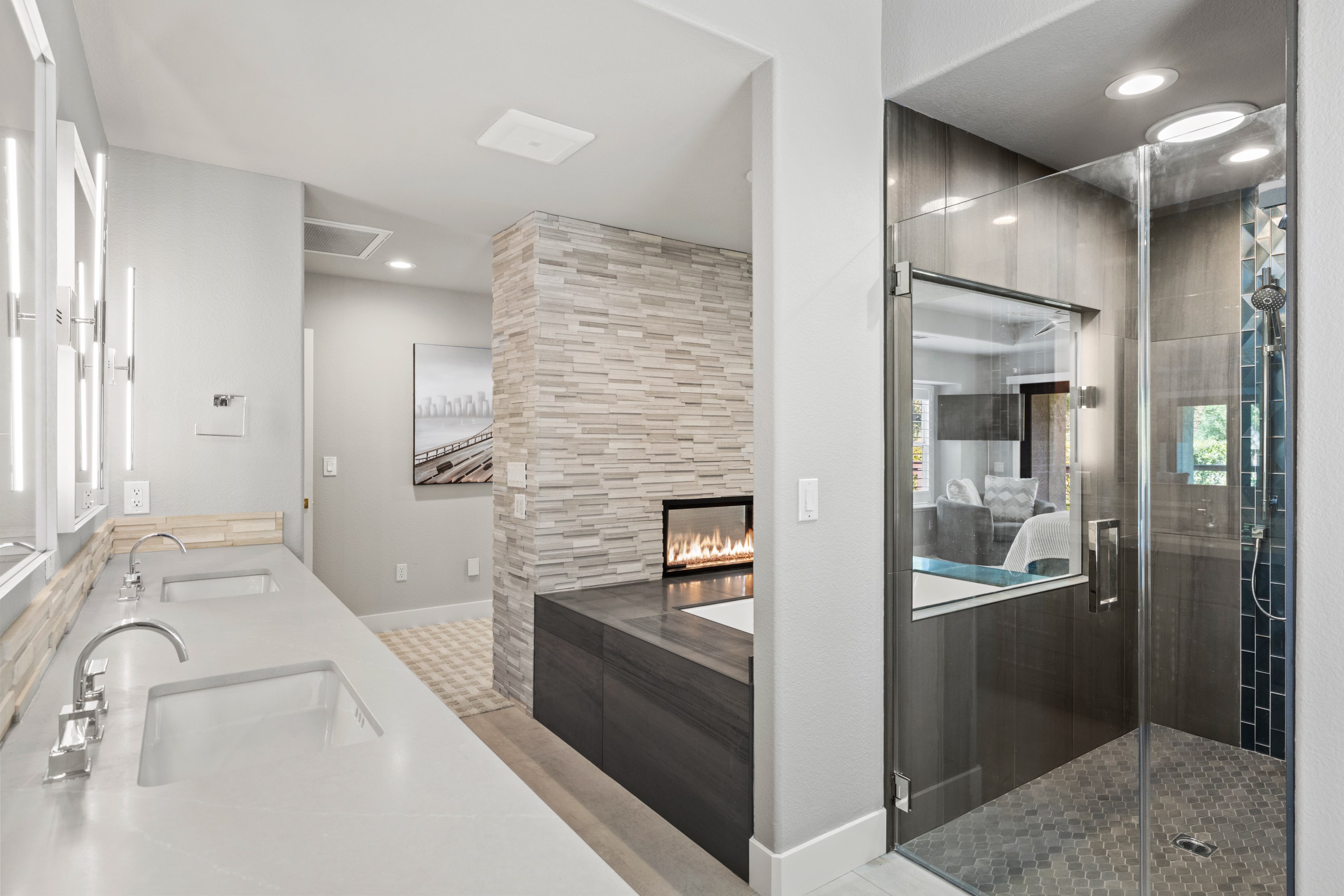 Remodeled master bath with quartz double vanity, stacked stone fireplace and frameless glass shower