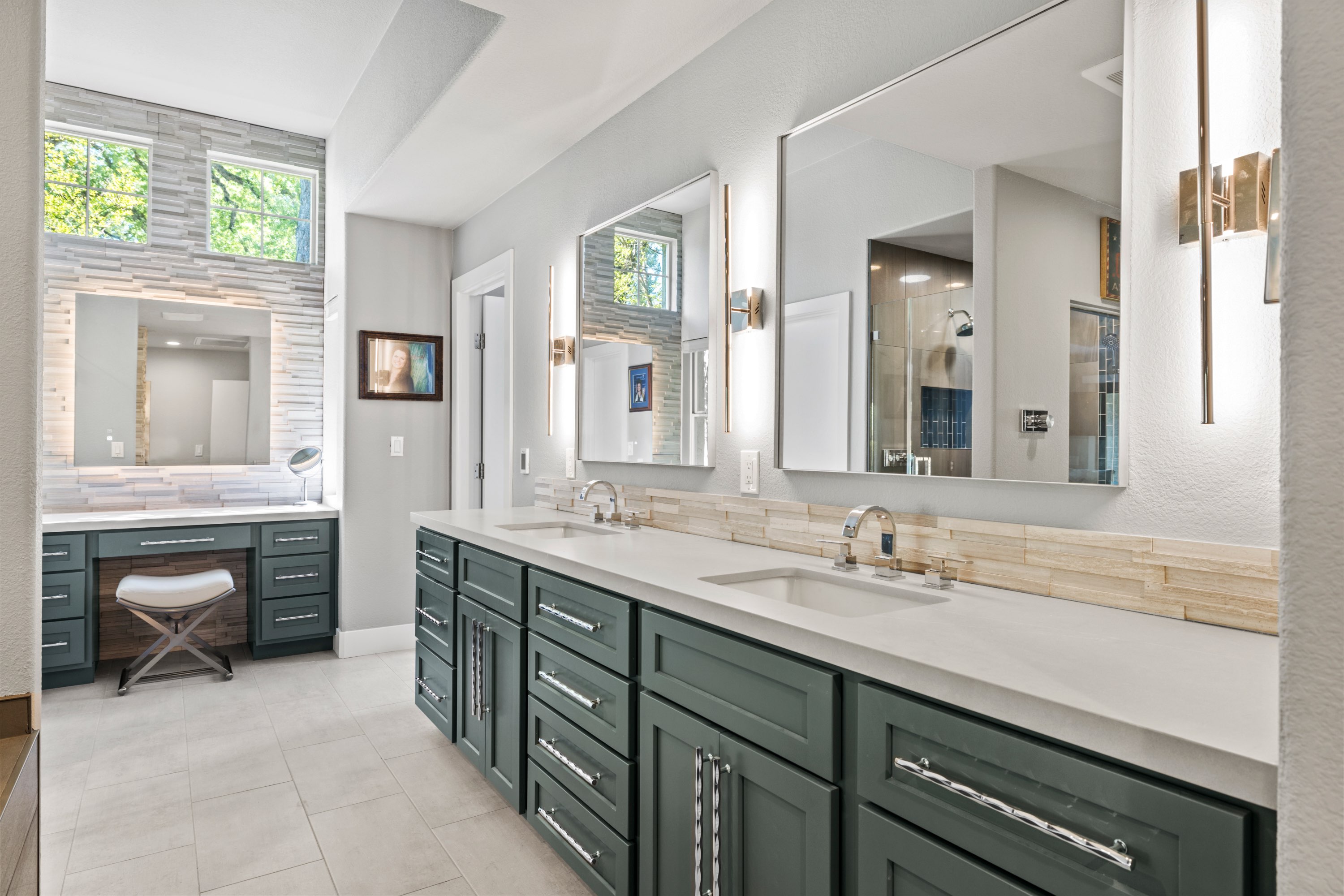 Deep green double vanity with quartz top, stone backsplash and a makeup station