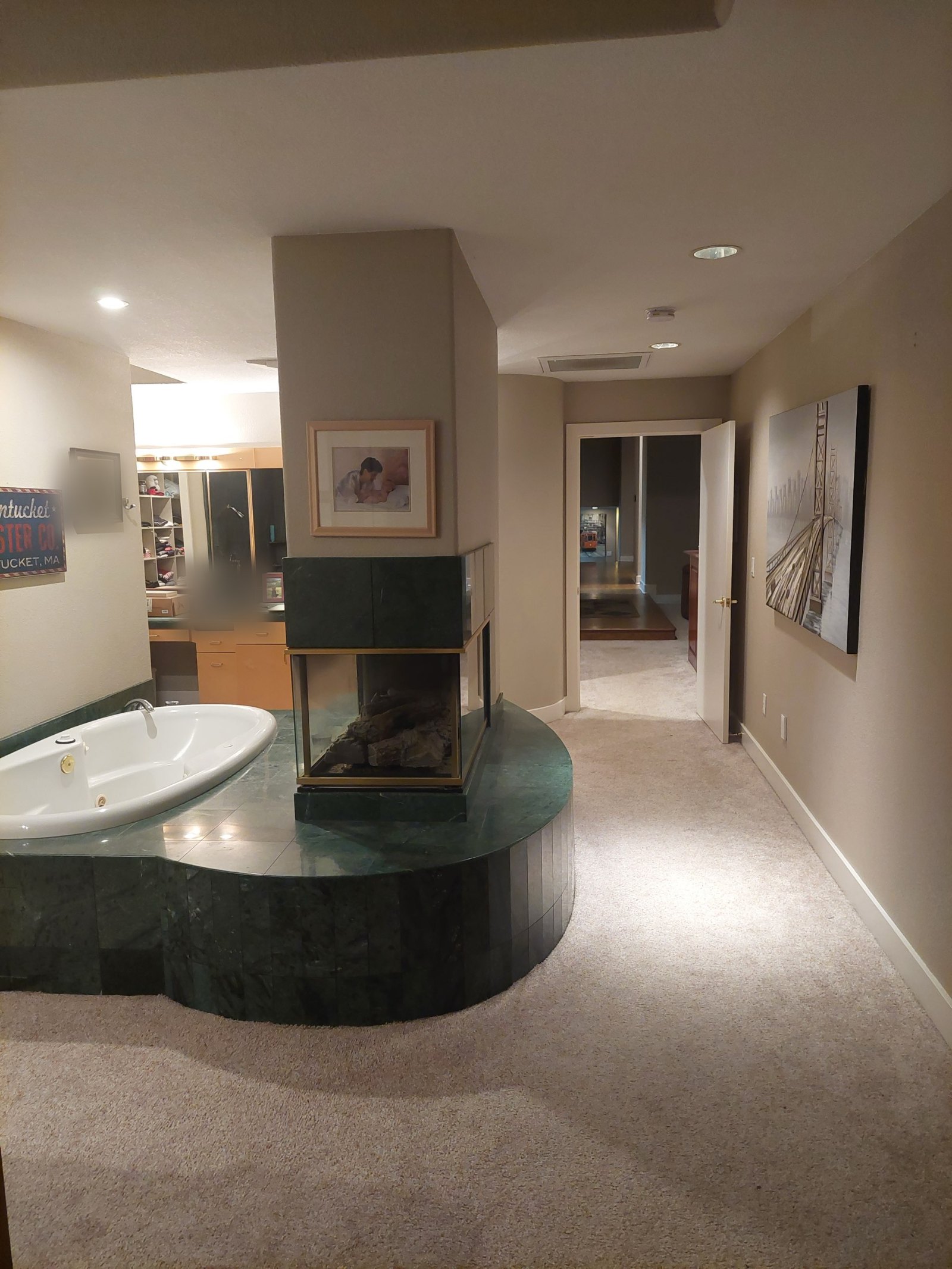 Original tub platform and fireplace seen from the bedroom hallway with carpeted floors